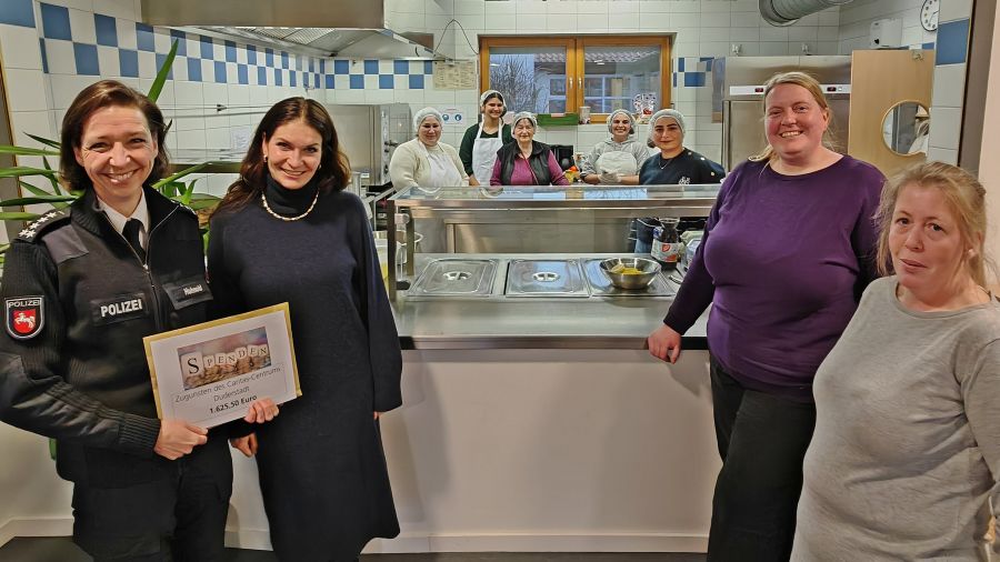 Das Foto zeigt eine Gruppe von Frauen, die Polizeihauptkommissarin trägt Uniform und hält einen symbolischen Scheck in der Hand.
