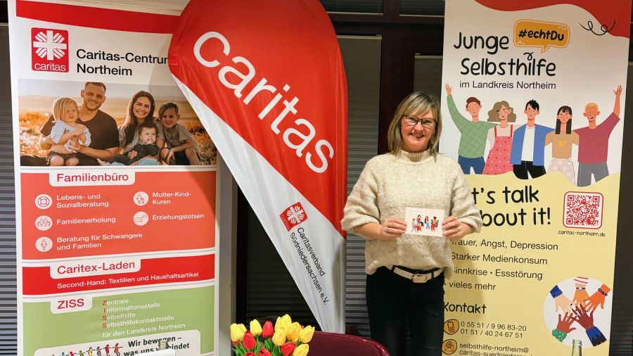 Das Foto zeigt Anna Holland an zwischen zwei Roll-Ups und einer Beach-Flag an einem Messestand.