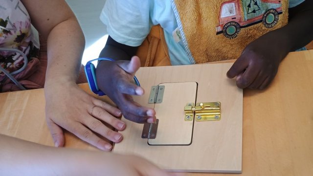 Das Foto zeigt mehrere Hände, die versuchen, ein Türschloss zu öffnen.