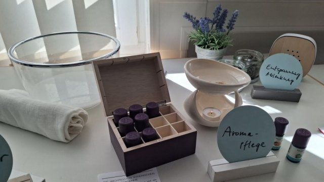 Das Foto zeigt einige Hilfsmittel bei der Sterbebegleitung, beispielsweise Fläschchen mit Aromatropfen, eine Glasschüssel und ein Handtuch.