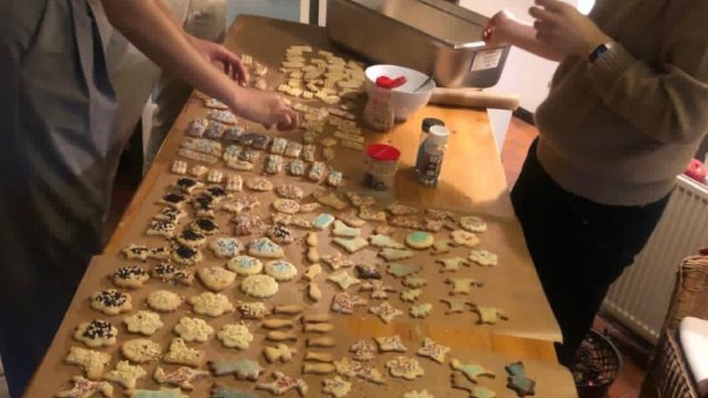 Das Bild zeigt, wie mehrere Menschen Weihnachtsplätzchen verzieren.